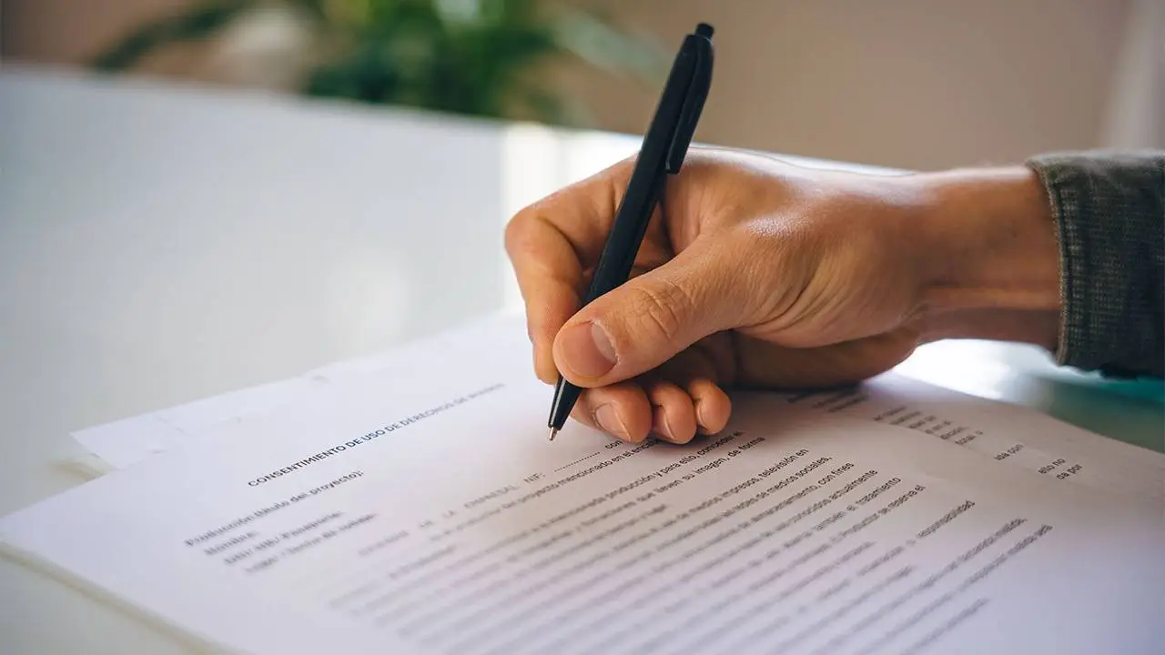 mano firmando un modelo de cesión de derechos de imagen